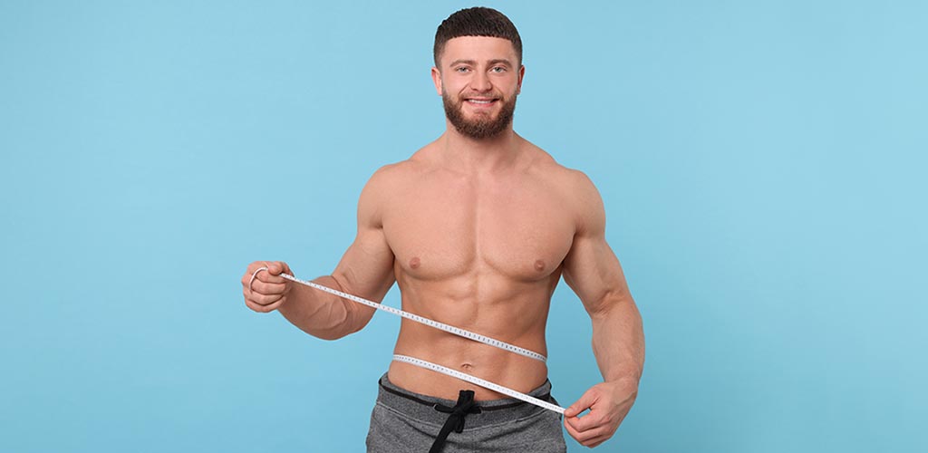 BodyTite Liposuction for Men: Phot of happy athletic man measuring waist with measuring tape.
